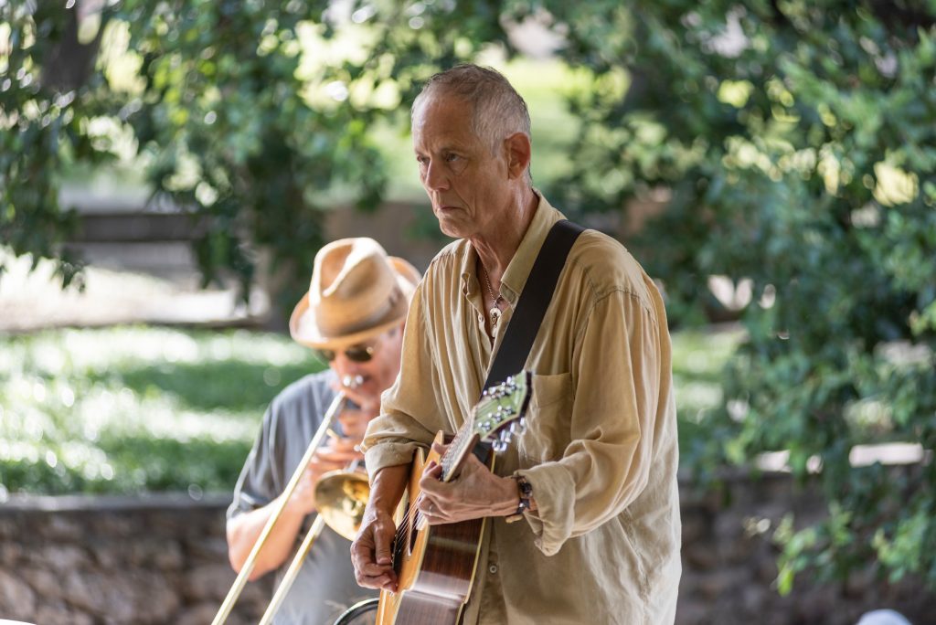 Rudi Harst playing guitar at a community gathering in the park