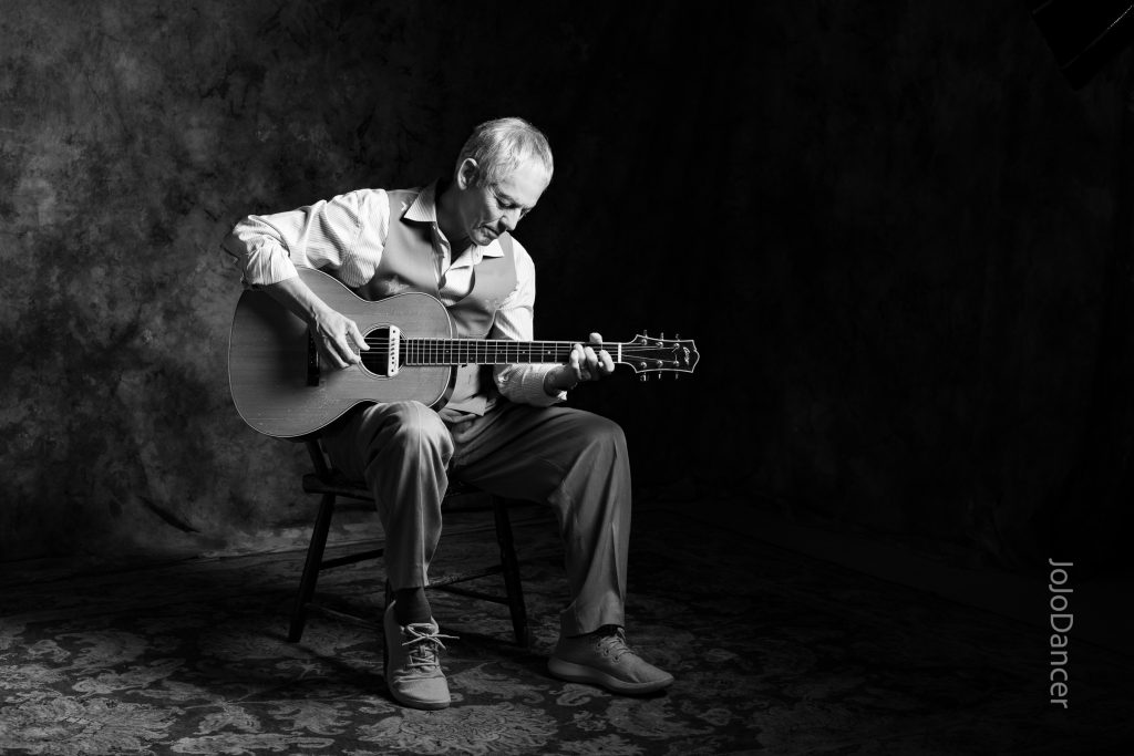 Black-and-white portrait of Rudi Harst with acoustic guitar