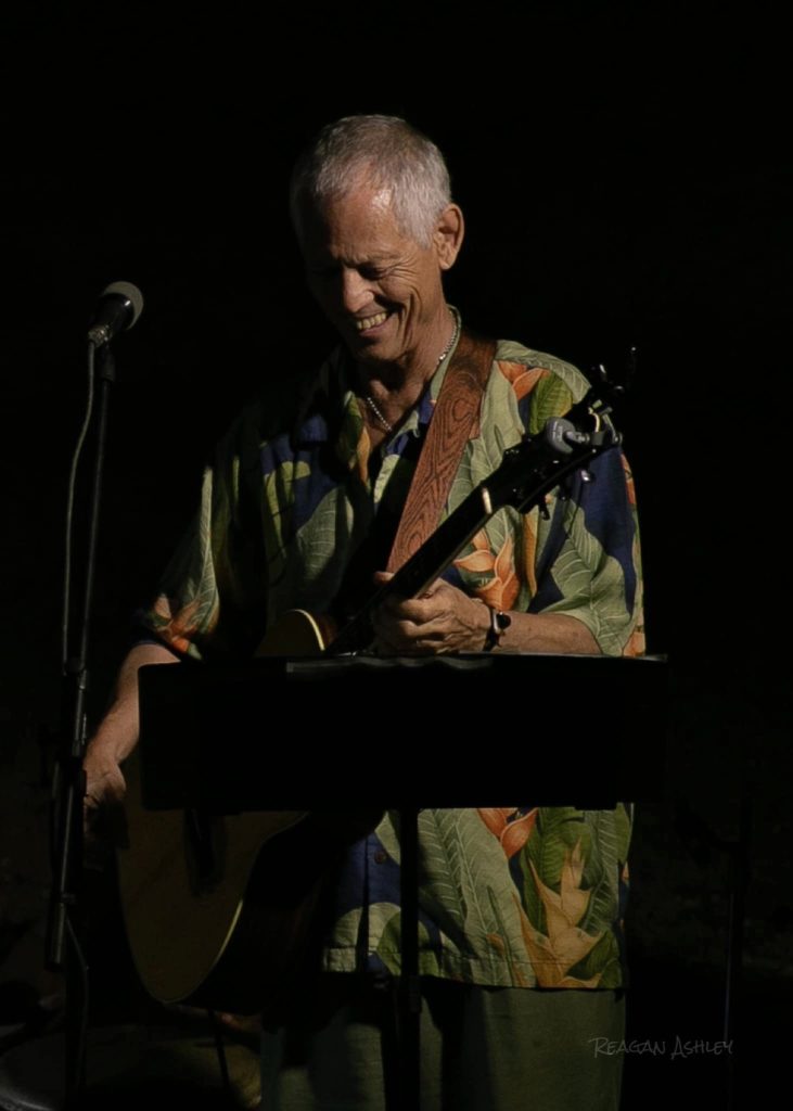 Rudi Harst playing flute under stage lights