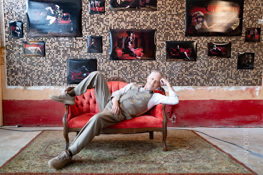 Rudi Harst relaxing on a red sofa
