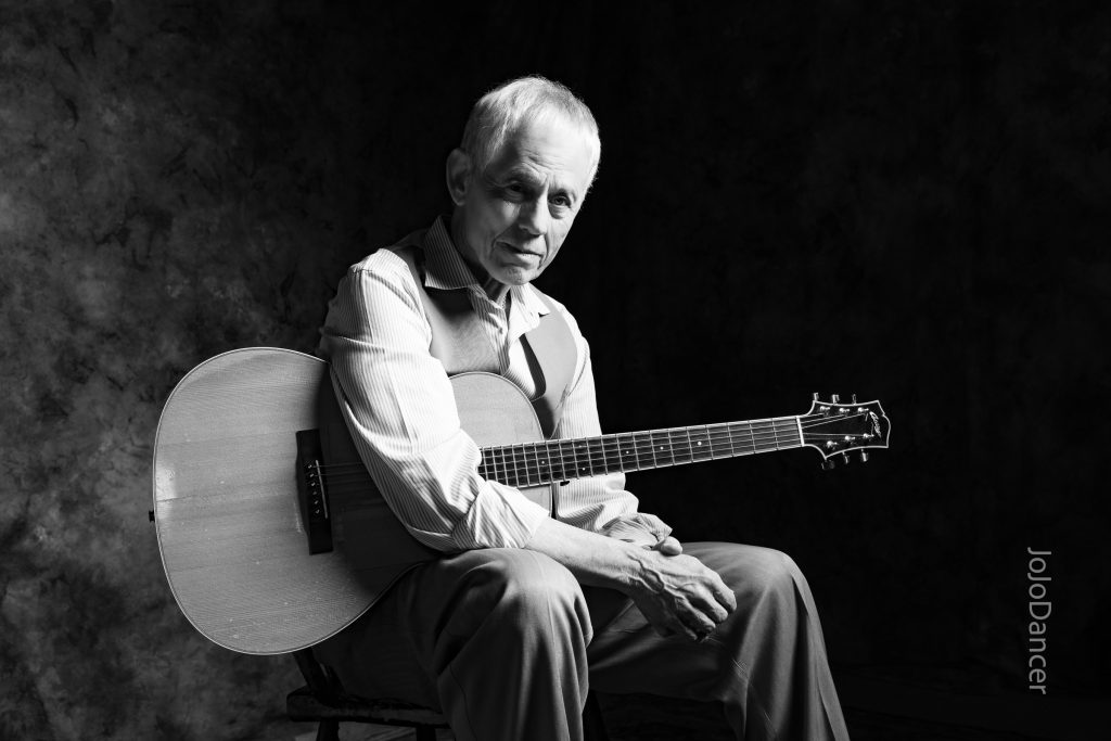Black-and-white portrait of Rudi Harst with guitar