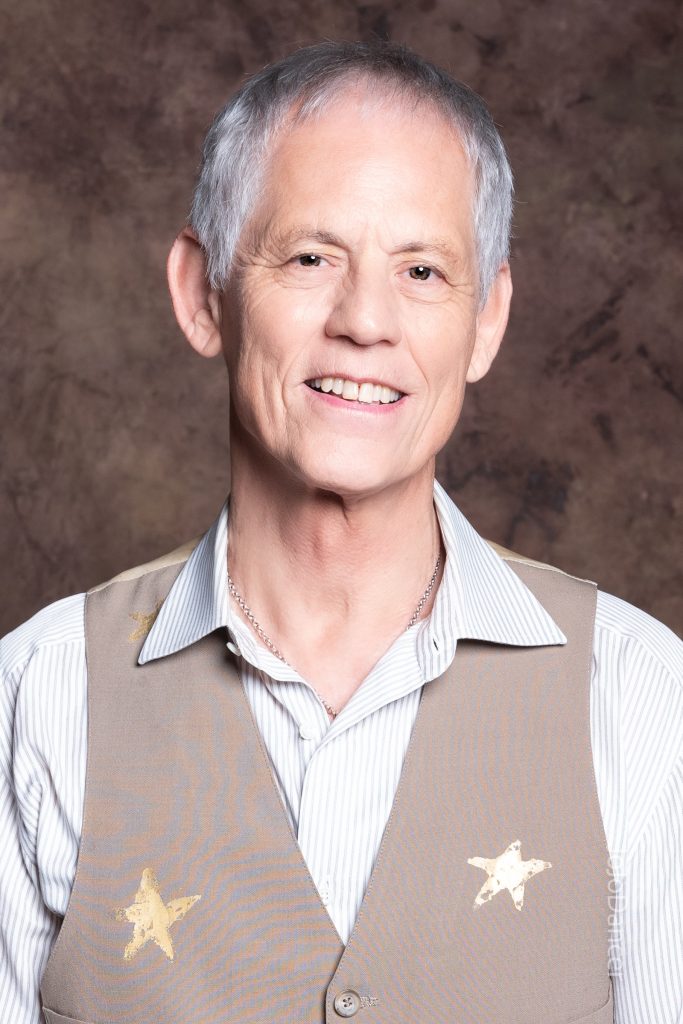 Rudi Harst smiling in a polished studio portrait