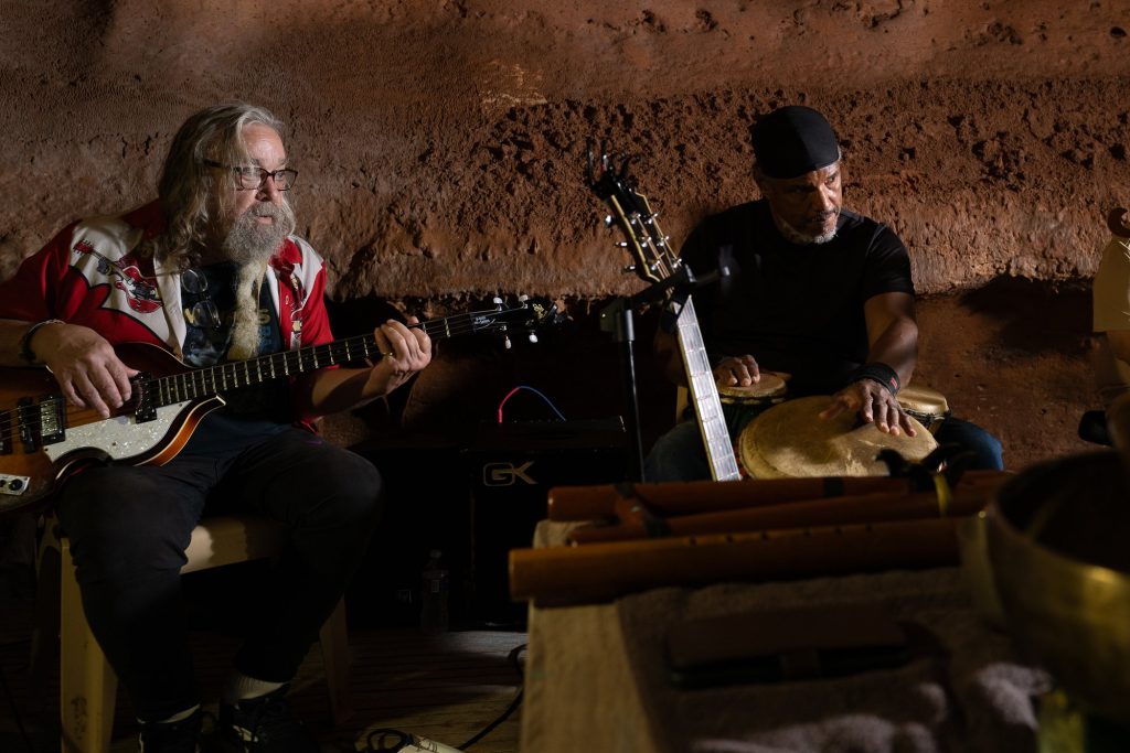 A bassist and percussionist playing beside an array of small instruments