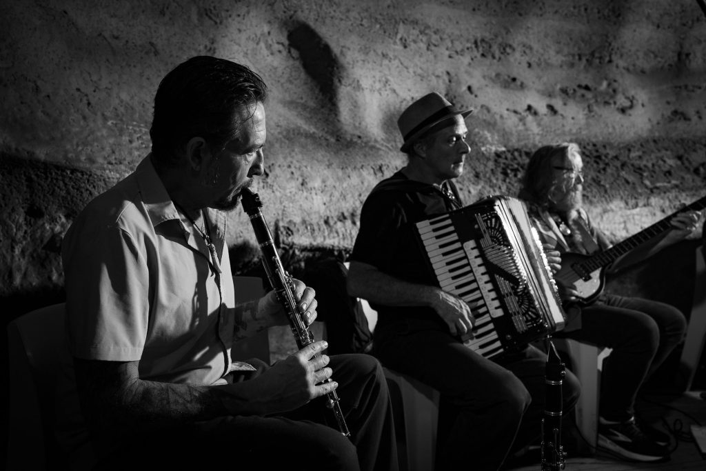 Monochrome view of a wind player, accordionist and bassist seated in a row