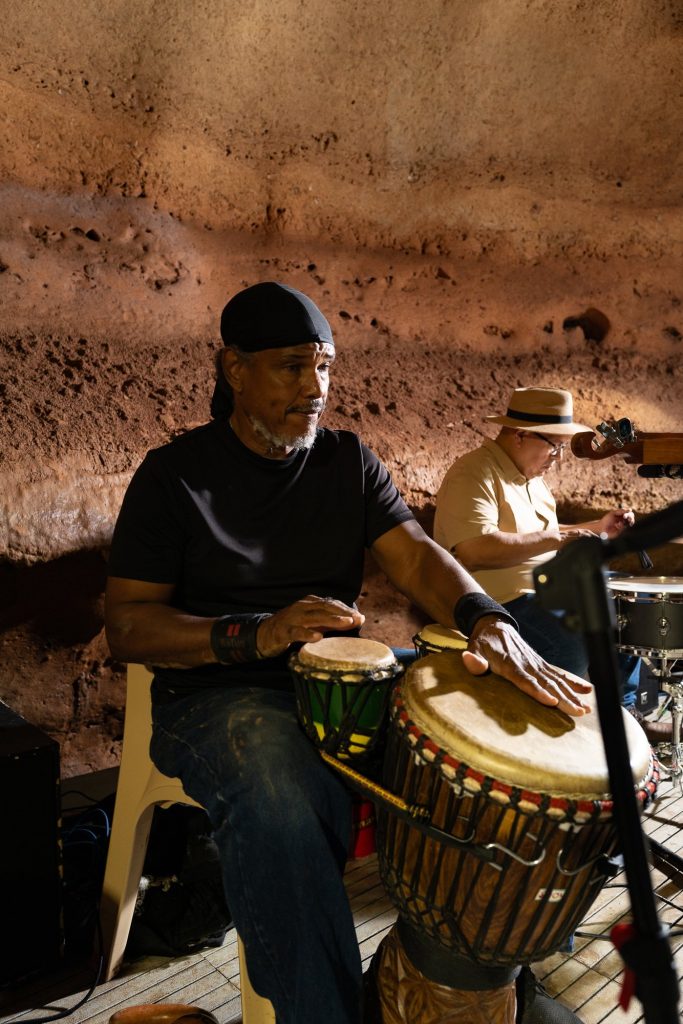 A percussionist playing two hand drums with a drummer behind him