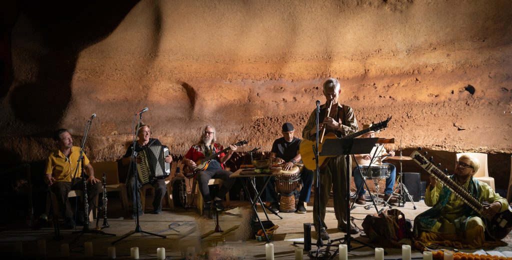 Wide view of Rudi Harst and the ensemble arranged across the cave stage