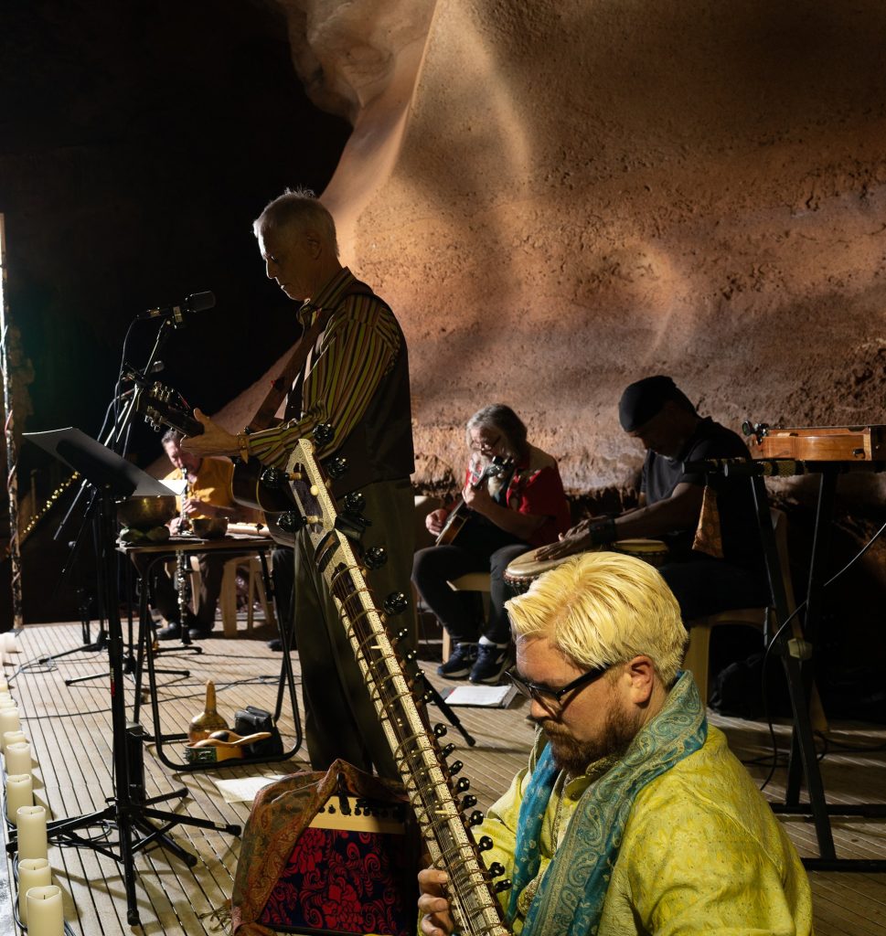 Side view of Rudi Harst with guitar and a seated sitar player