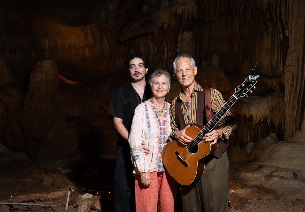 Rudi Harst posing with two visitors beneath cave formations