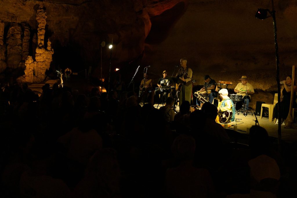 A dimly lit view across the audience toward the cave stage