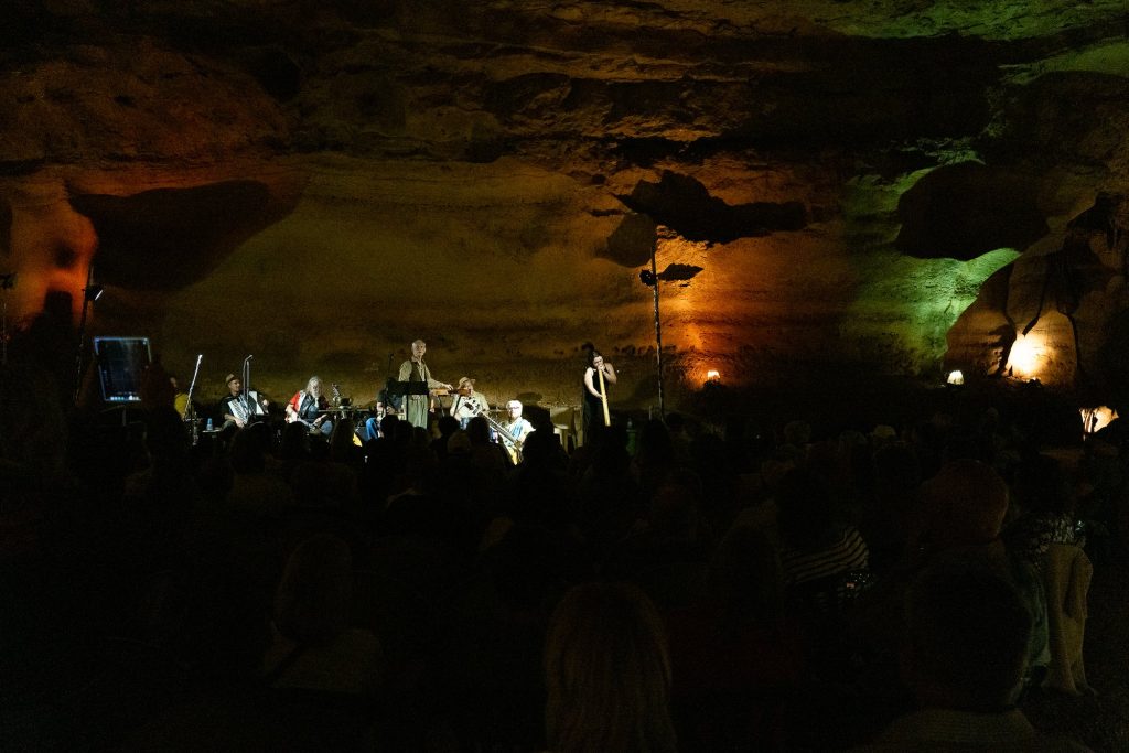 Wide view of the stage and audience beneath amber and green cave lighting