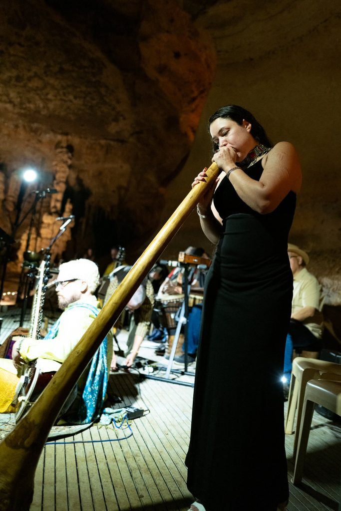 Vertical view of a musician in a black dress playing a long wooden wind instrument