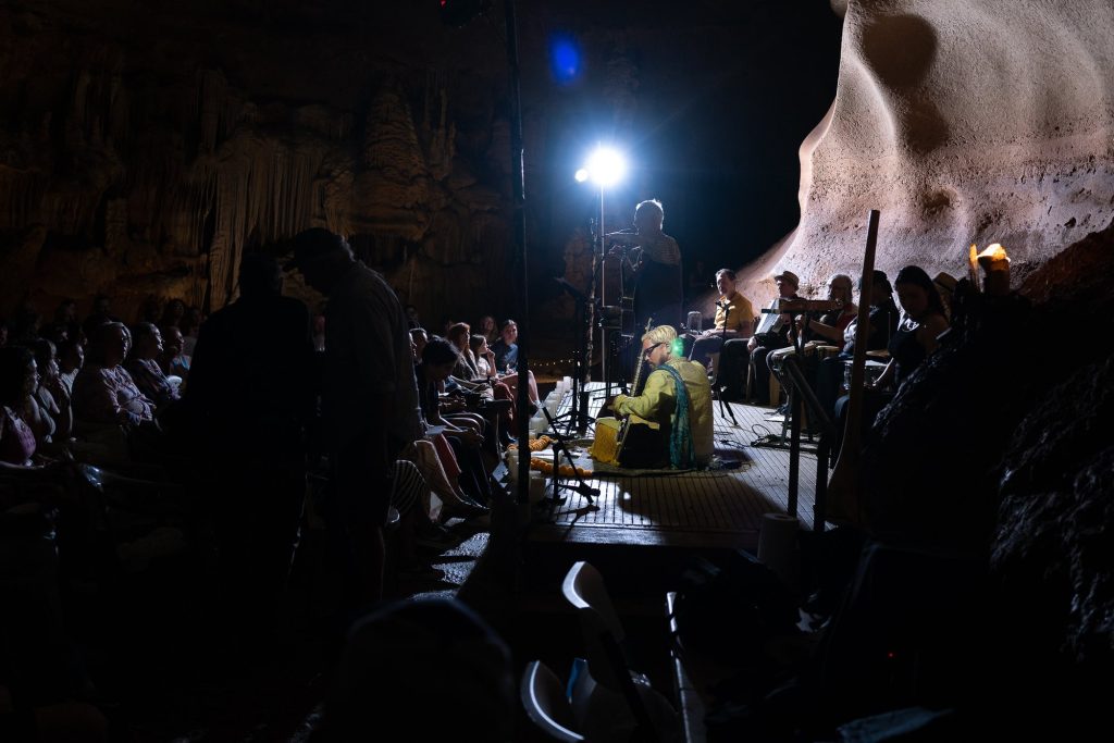 Side view of the stage and seated audience framed by dark cave walls