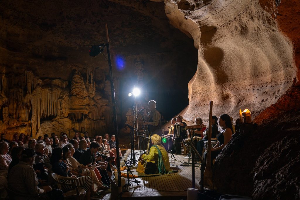 Concertgoers watching Rudi Harst and the ensemble beside illuminated cave formations
