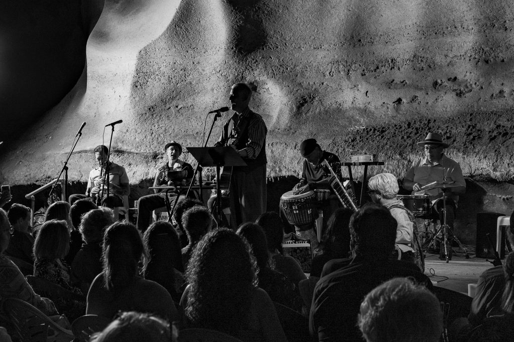 Closer monochrome view of Rudi Harst performing for the cave audience