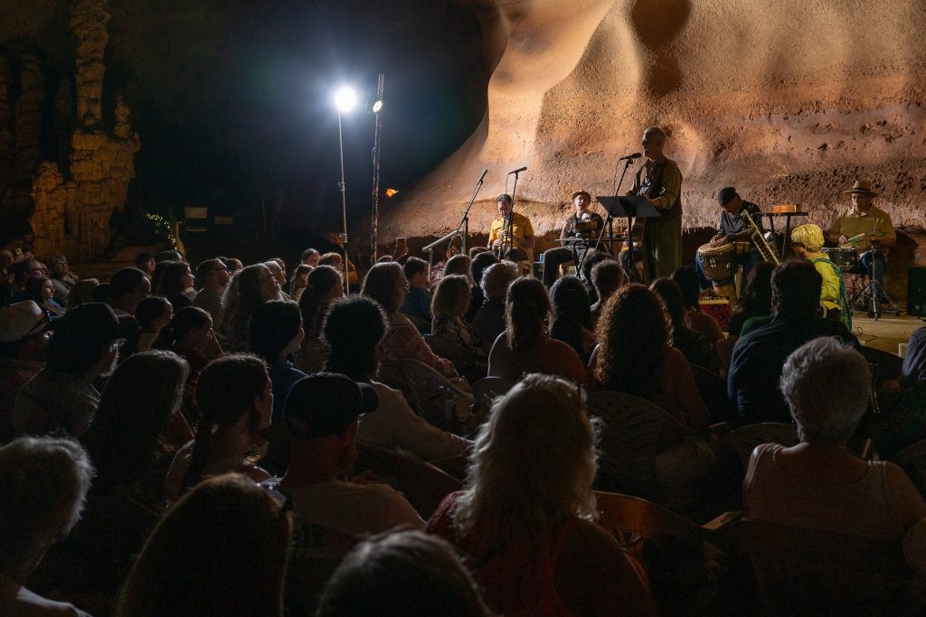 The cave audience watching Rudi Harst and the ensemble under stage lighting