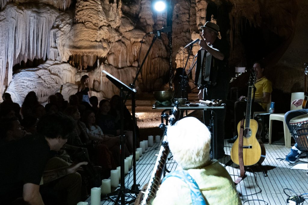 A standing wind player performing near a microphone with the audience beside the stage