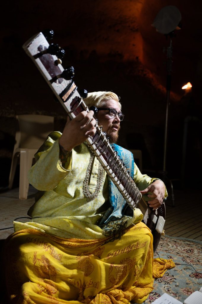 Vertical portrait of a seated musician playing sitar