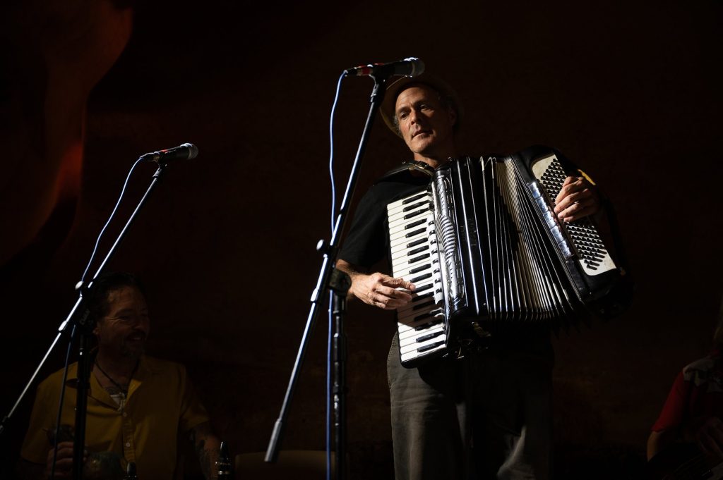 A standing accordionist performing at a microphone