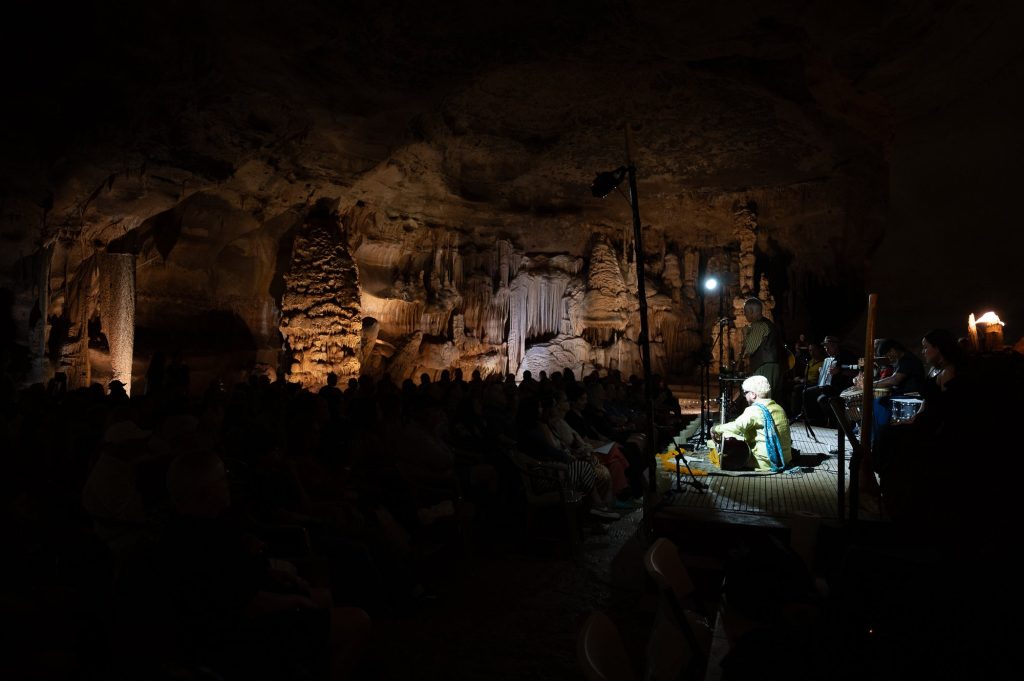 Vertical view of the cave audience and the brightly lit sitar player